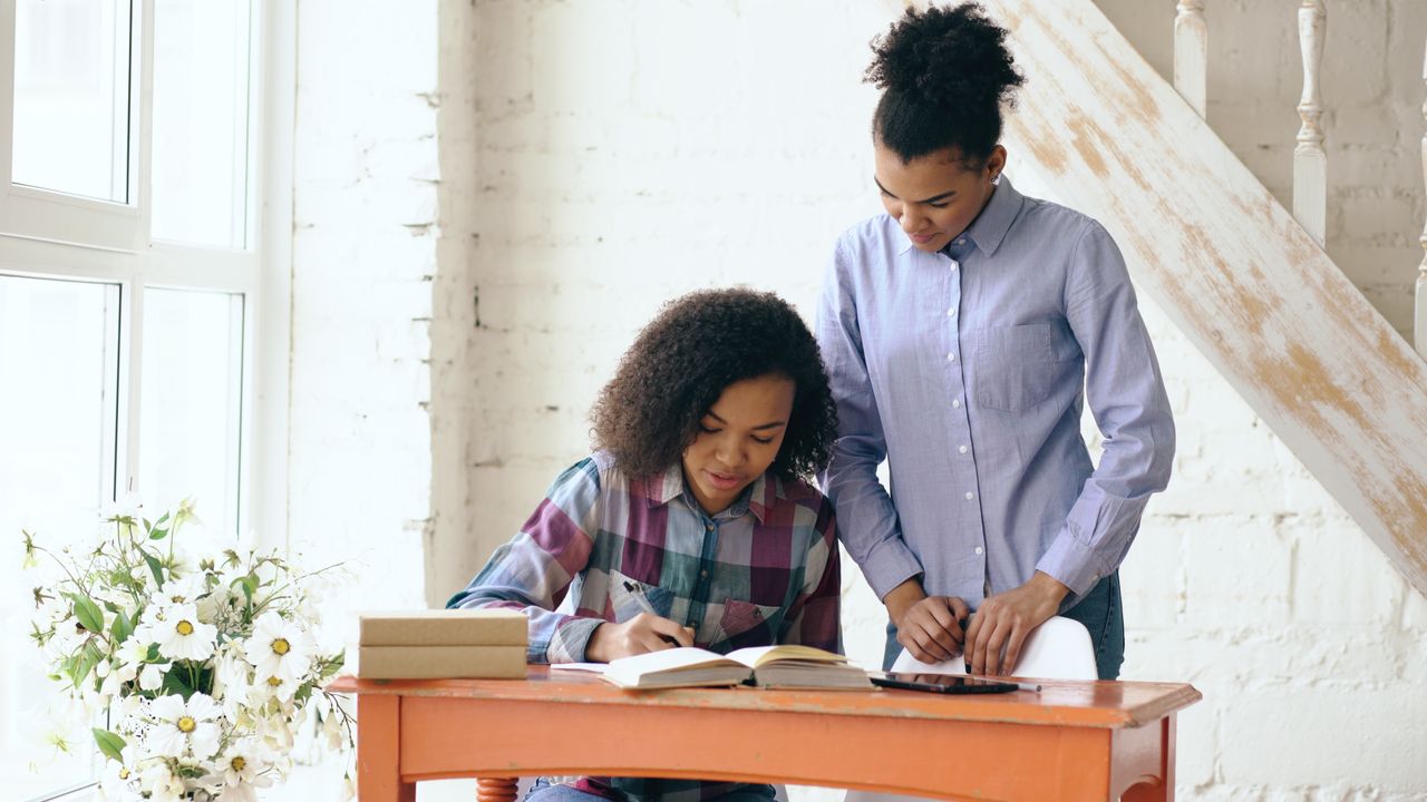 Accueil Mother helping daughter with homework at home in warm daylight.