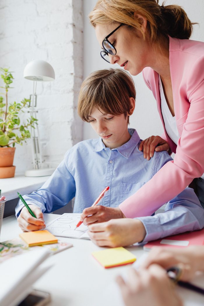 Accueil Teacher helping a student with homework at a desk indoors.